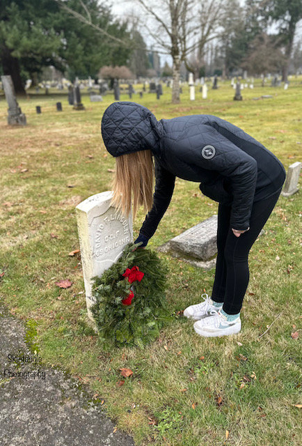 Attendee in black placing a wreath.